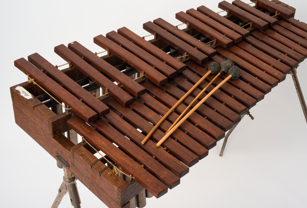 Marimba med tilhørende køller, stativ og kasse. 

Instrumentet har kromatisk skala, arrangert som på et piano. Det er i alt 37 trestaver fordelt på to høydenivåer.

Materiale: ek, blikk, jern, hamphyssing, bambus, Etui papp, lær, blikk, stål. Det er resonansrør, to trestativer for tangentene, to tre-endestykker, stativ, to køller med bambusskaft og garnkledde gummikuler, en kølle med ullgarnkule, og kasse.
