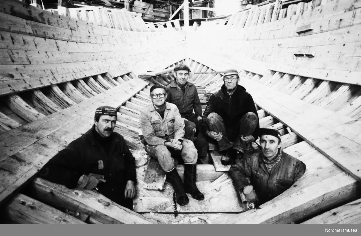Ola Kjøl (fra venstre) Ivar Sveggen, Kristoffer Gjøten, Torvald Strand og Halvor Kongshaug var alle ansatt ved Bremsnes båtbyggeri i 1985. En 49 fot fiskebåt var underbygging og de var i forhandlinger om to båter til. Bransjen sto derimot i et veiskille. Holdningen hos myndighetene var at trebåter som større fiskebåter skulle fases ut. Nye båter skulle bygges i aluminium og stål. (Foto: Roald Sevaldsen)   - Bremsnes båtbyggeri. Bildet er fra avisa Tidens Krav sitt arkiv i tidsrommet 1970-1994. Nå i Nordmøre museums fotosamling.