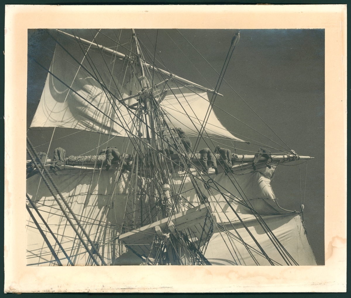 Bilden visar verksamhet ombord på skeppsgossefartyget Jarramas. Manskapet har klättrat upp på riggen och håller på att sätta eller bärga segel.
Fotot är taget under något av åren 1940-talet, då fartyget var bemannat av elever från Sjömannsskolan.