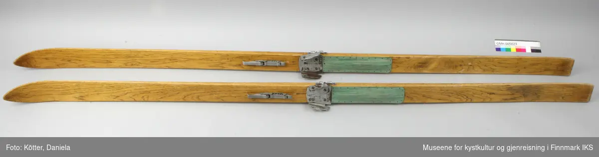 Hoppskiene er laget av treverk og overtrukket med en transparent lakk. Skiene har Kandaharbindinger der metallwirene mangler. Der skoene står på skiene er det spikret på  rektangulære biter av grønn mønstret kunststoff eller linoleum. 