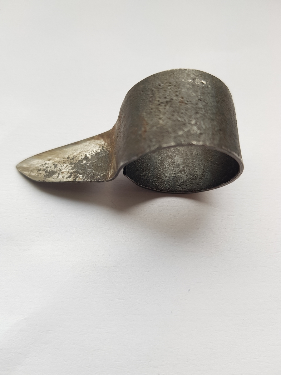 Et lite stykke metall formet som en runding med en utstikker som er en kniv