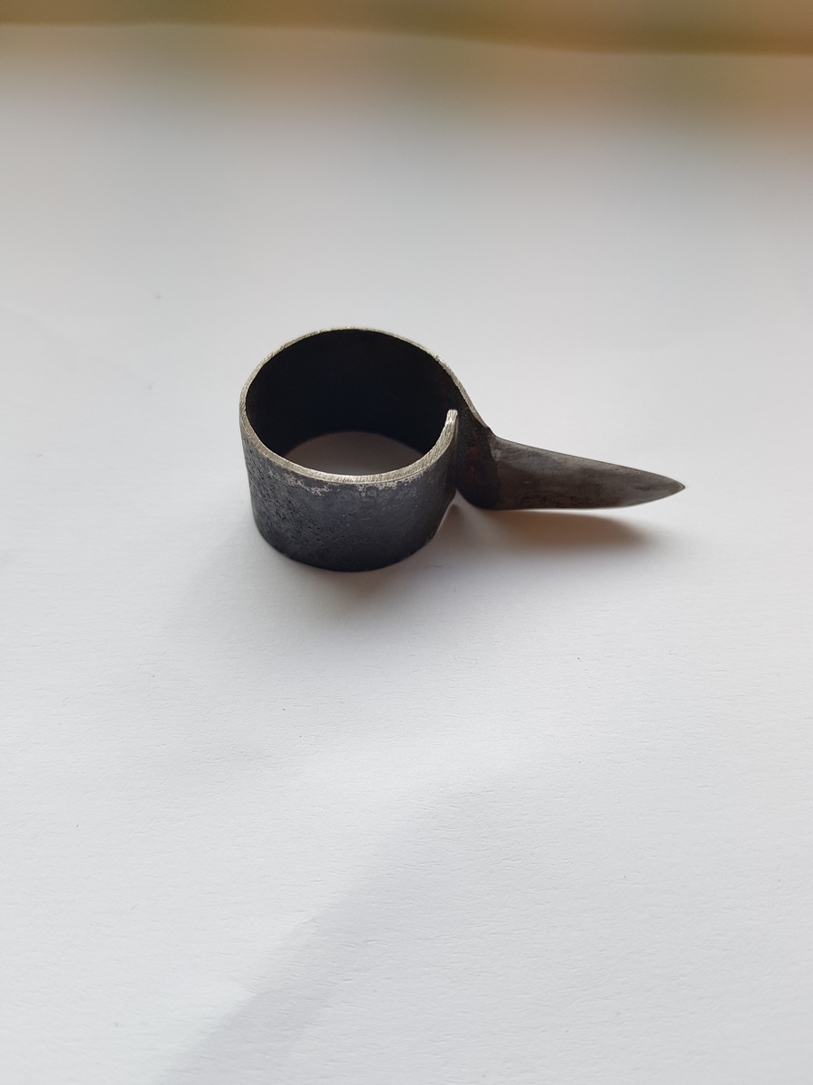 Et lite stykke metall formet som en runding med en utstikker som er en kniv