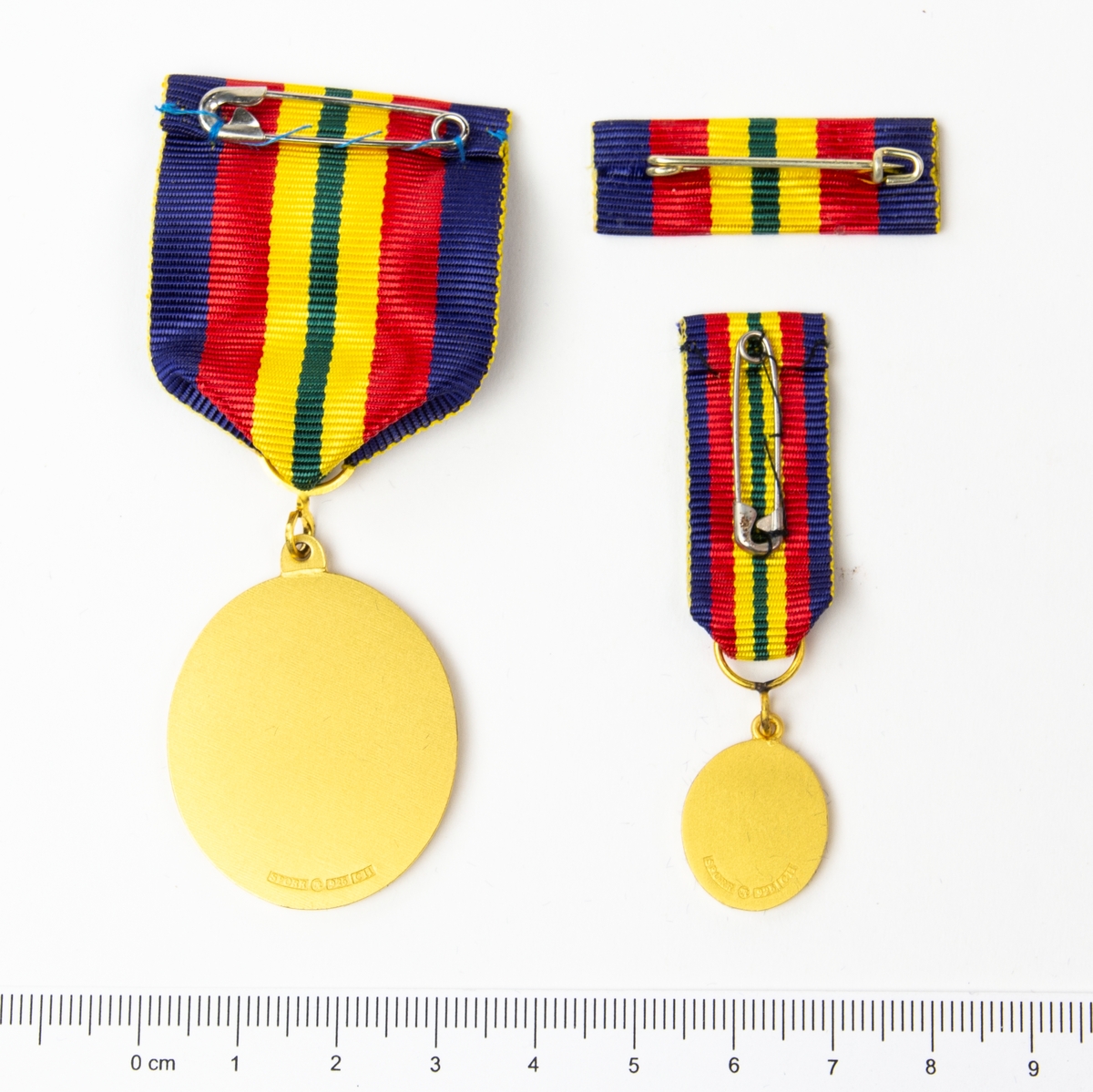 2 st medaljer och 1 st utmärkelsetecken. Framsida med lagerkrans, svärd och heraldiskt vapen. Förvaras i originalask.