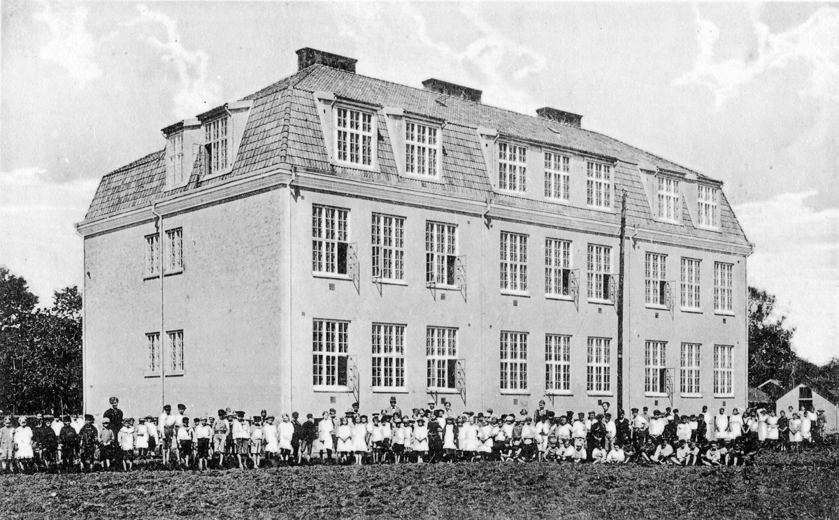 Vykort med Landsskolan, nuvarande Afzeliiskolan. Skolbyggnaden med elever och skolpersonal samlade utanför.