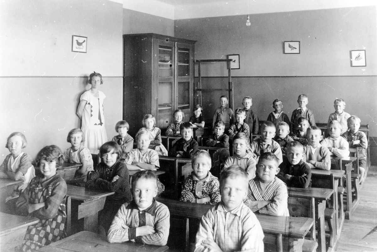 En klass på cirka 30 elever med sin lärarinna ståendes till vänster. En av eleverna är Bengt Andersson, okänt vem.