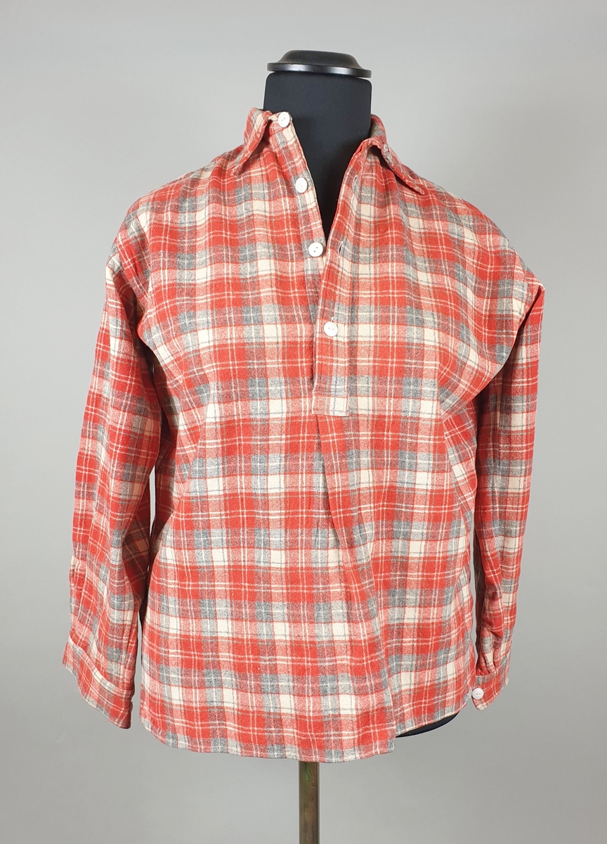 Rødrutete skjorte av ullflanell til kvinne, med skjortekrage og fire knapper i halsåpning. Lange ermer med knapp på mansjetten.