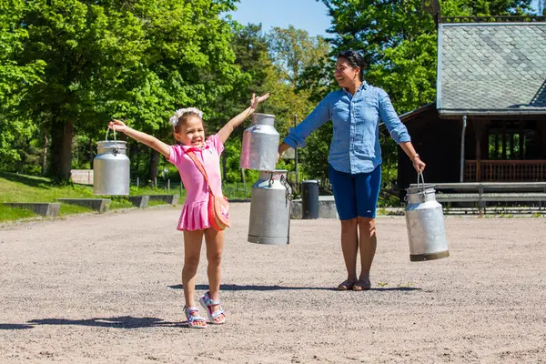 Mor og datter konkurerer i hvem som klarer å holde melkespannene lengst.