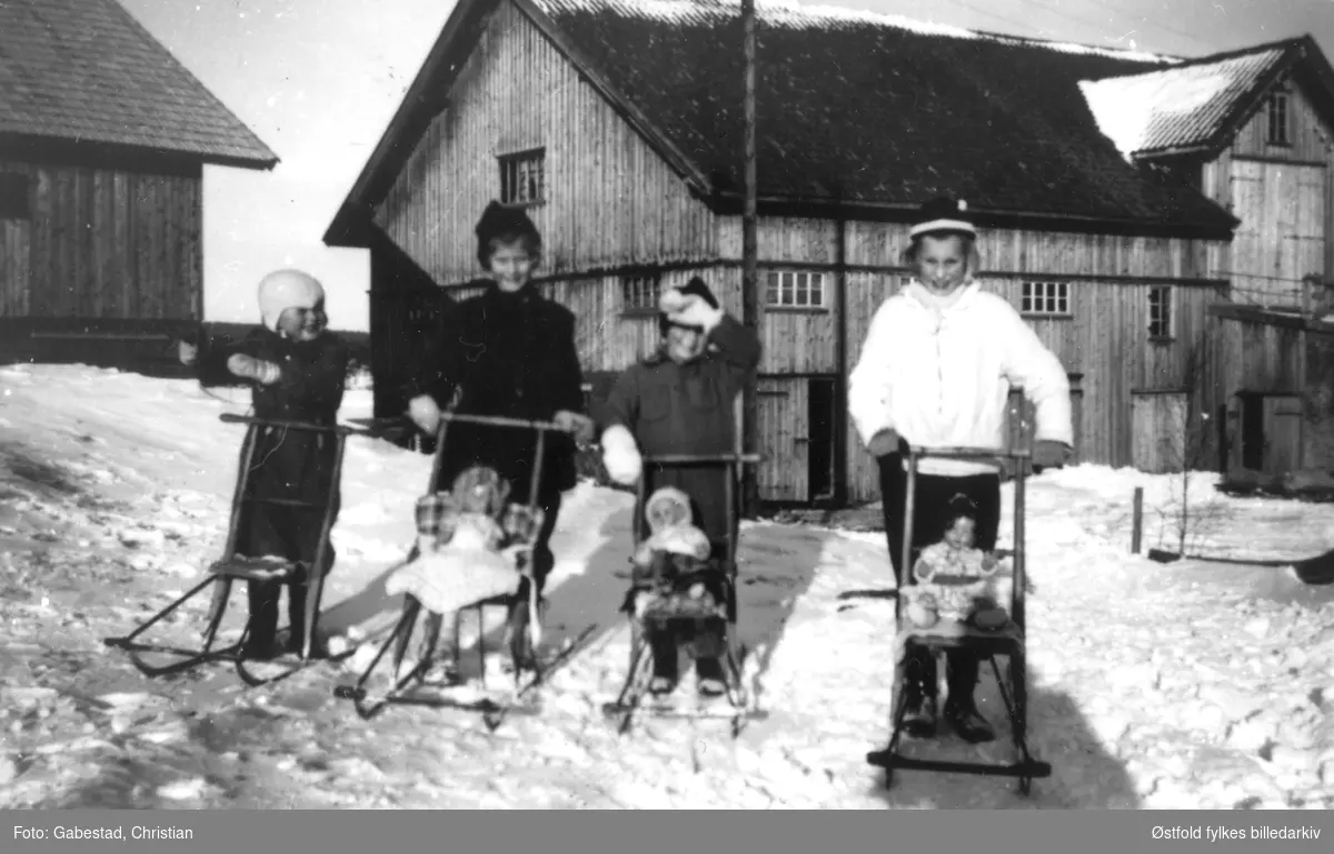 Sparketur med dukkene. Fra venstre Håvard og Torill (søsken). Åse Marit og Lill (søsken), alle Gabestad som etternavn. I bakgrunnen to Gabestad-gårder som ligger helt inntil hverandre. Bildet er ant. tatt ca. 1950.