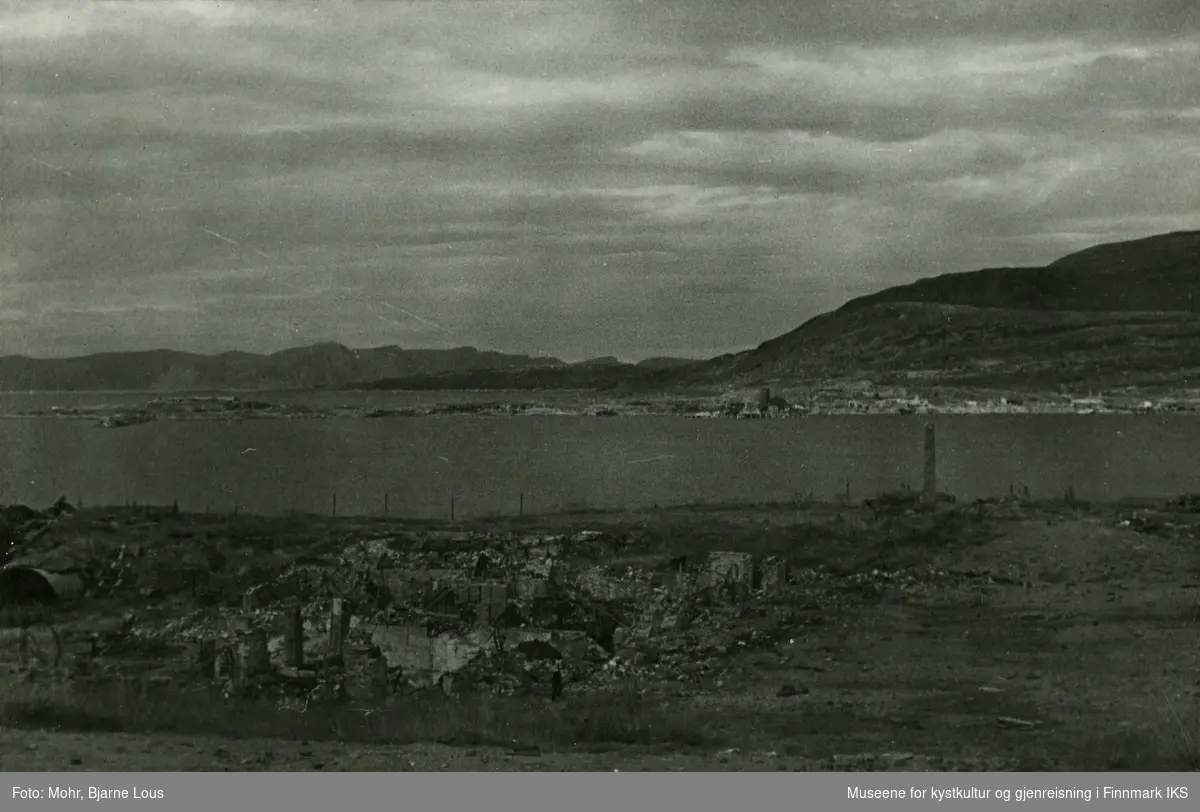 Ruiner i Hammerfest sentrum etter andre verdenskrig. I bakgrunn ser man Fuglenes og Melkøya. Kan søyla man ser i bildet, være minnebauta som ble reist i 1909, hundre år etter engelskmennenes angrep på Hammerfest?