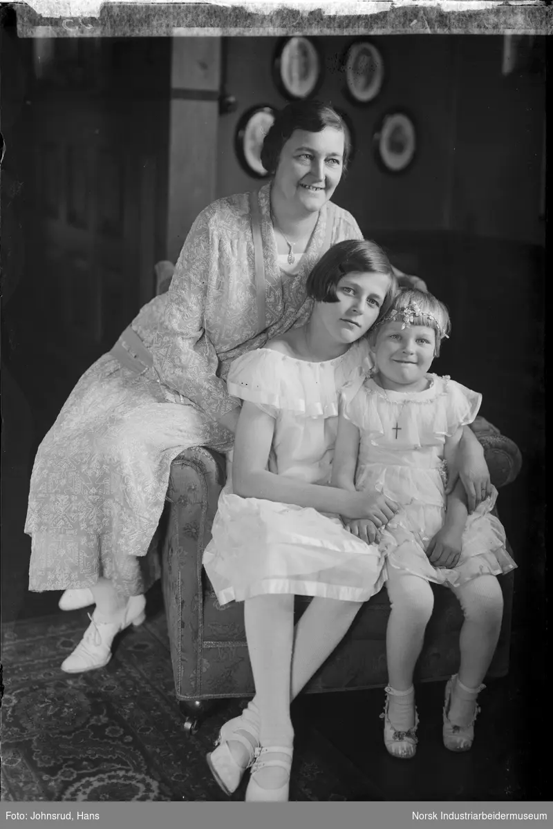 Gruppeportrett. Kvinne med to barn sittende på stol i stue. Alle i kjoler.
Portrett bestilt av Direktør Hansen.