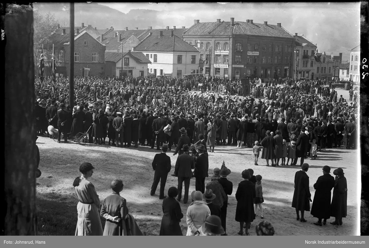 17. mai feiring på Torget 1932. Folkemengde samlet på torget. Korps marsjerer. Hotell Bondeheimen i bakgrunnen.