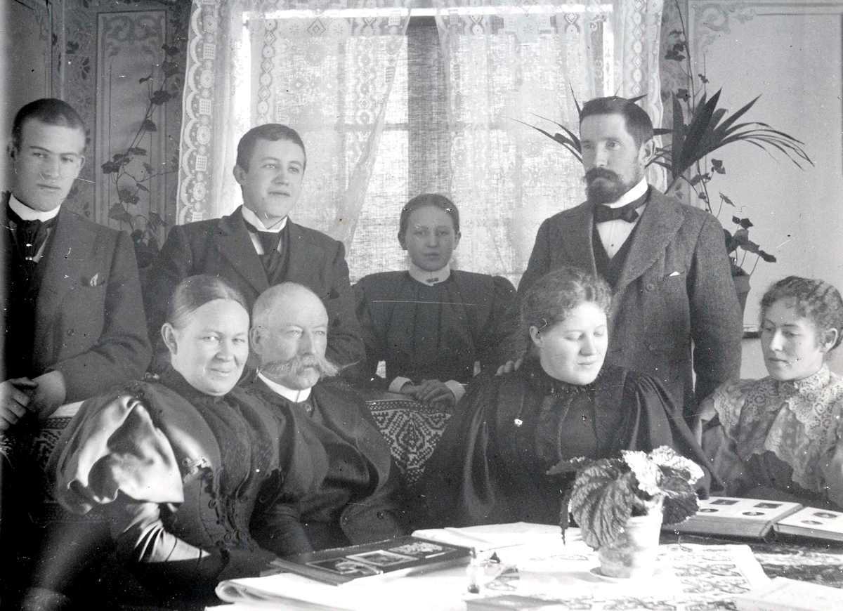 Ringsaker, Veldre, Løken østre, familiegruppe, foran fra venstre: Antonette Ring født Todderud (1854-1919), rittmester Paul Ring (1843-1909), Wilhelmine Løken (Mimi) (1876-1953), antatt: Antonette Barbara Ring (Lally) gift Skappel (1877-), bak fra venstre: Barthold Ring (1881-1951) Paul Ring (1879-1907), Antonette (Tulla) Ring (1883-) gift Hersaug og Ole Løken (1860-1924), interiør stue, ser på fotoalbum, 
Mimi, Lally, Tulla, Paul og Barthold er barn av Paul Ring og Antonette Ring