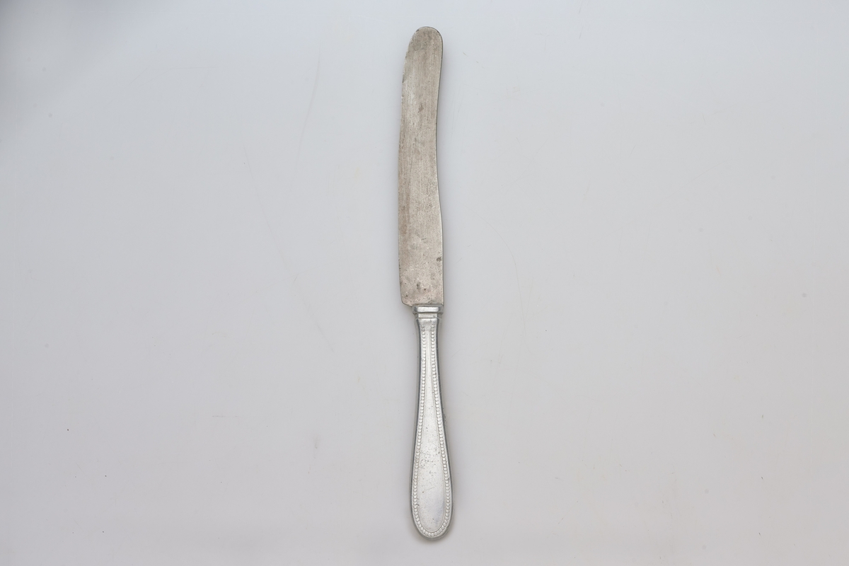 Hele kniven er av stål, vanlig utførelse, enkelt mønster på håndtaket, fabrikklaget. I enden av håndtaket er innrisset bokstaven P.