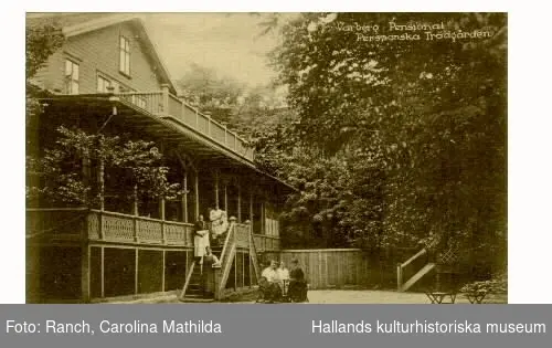 Vykort, "Varberg, Pensionat Perssonska Trädgården." Stavningen på denna inrättning har varierat och benämns ofta som Restaurang Pehrssonska trädgården. Här står tre kvinnor i trappan, en med en baby, och tre kvinnor sitter kring ett bord nedanför trappan. Troligen 1910-tal.