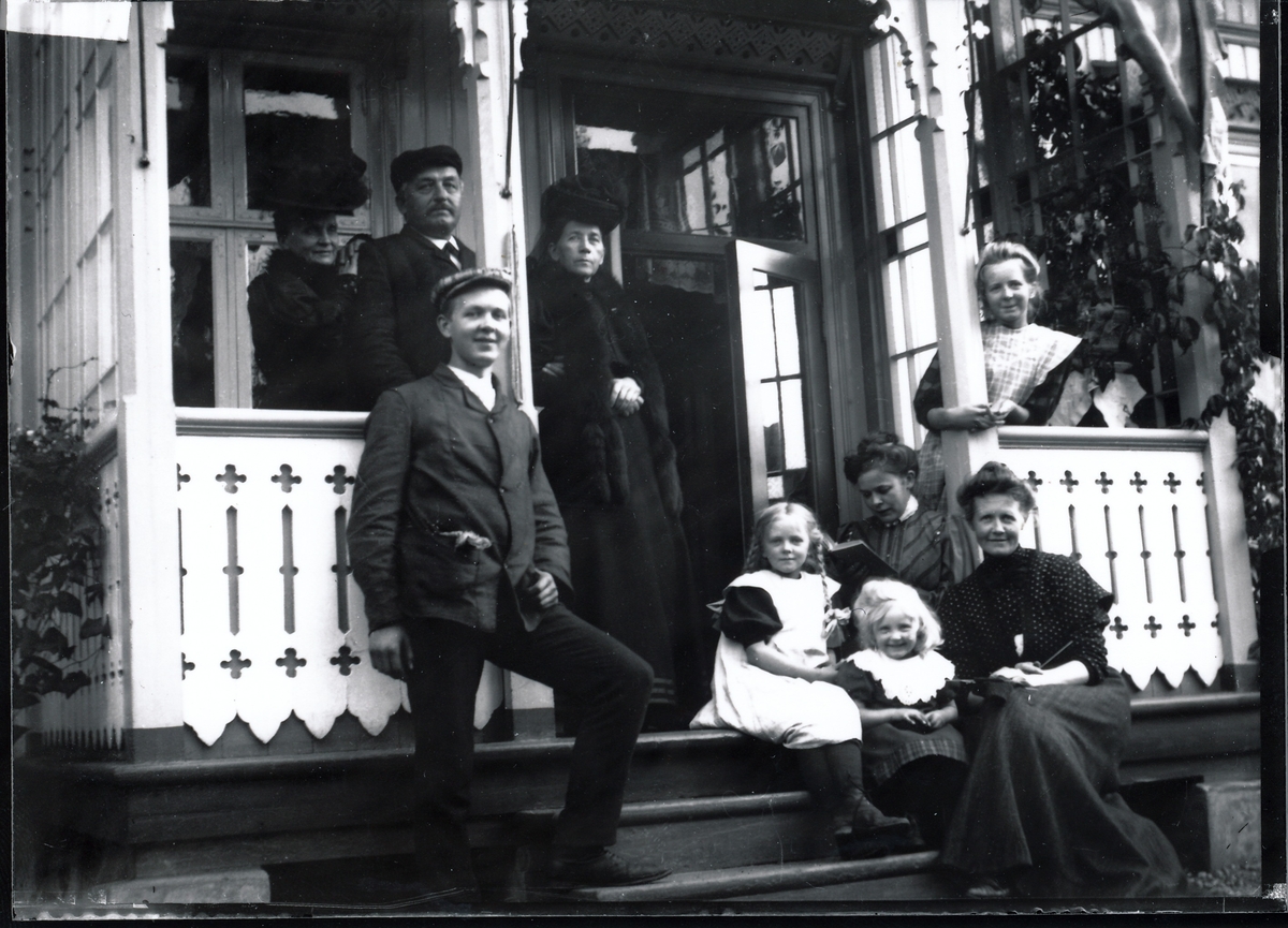 Medlemmer og venner av Rydgrenfamilien står og sitter på verandaen utenfor bestyrervillaen på Kistefos Træsliberi.