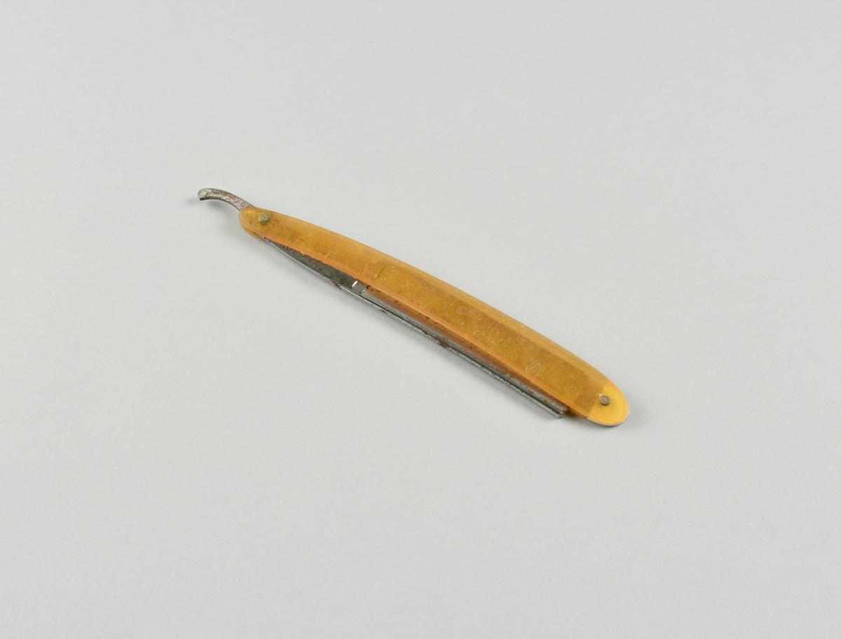 Sammenleggbar barberkniv med skaft i ravfarget materiale.