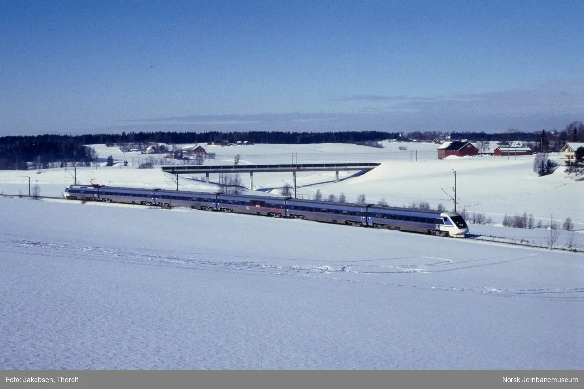Svensk elektrisk motorvognsett type X2 med tog til Oslo S ved ca. km 28,5 ved like syd for Holstad stasjon på Østfoldbanen. I bakgrunnen Bølstadbekken bru på det nye dobbeltsporet