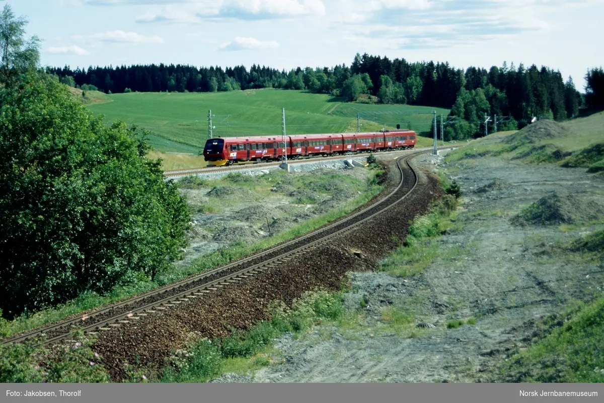 Elektrisk motorvognsett type 70 med styrevogn ABS 70 607 fremst, med tog fra Göteborg til Oslo S, tog 386, ved ca. km 34 mellom Ås og Vestby. Gammel trase ved Høyåssvingen i forgrunnen
