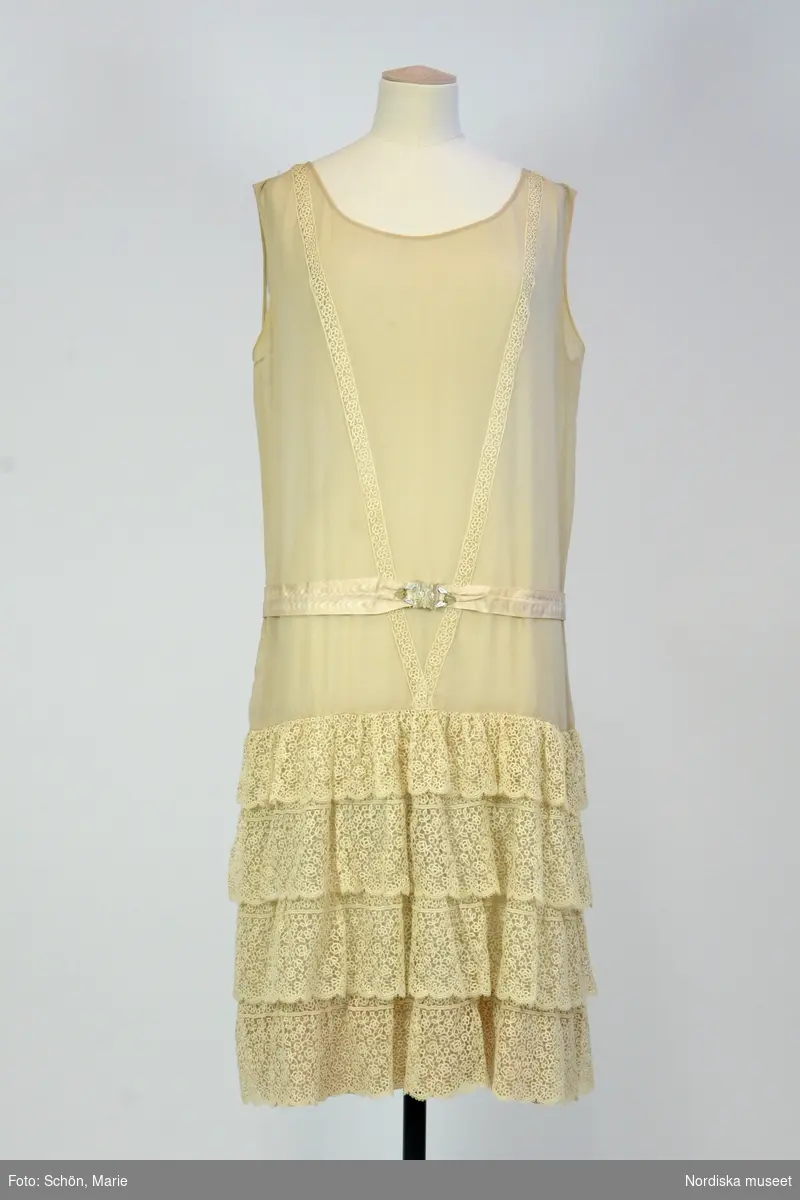 Ordered by Kerstin Stafsing née Jonsson (1899–1986). Delivered ca. 1925. Chiffon evening dress with lace flounces and a mother 
of pearl belt buckle in the shape of an owl’s head. Possibly after an original by Coco Chanel.