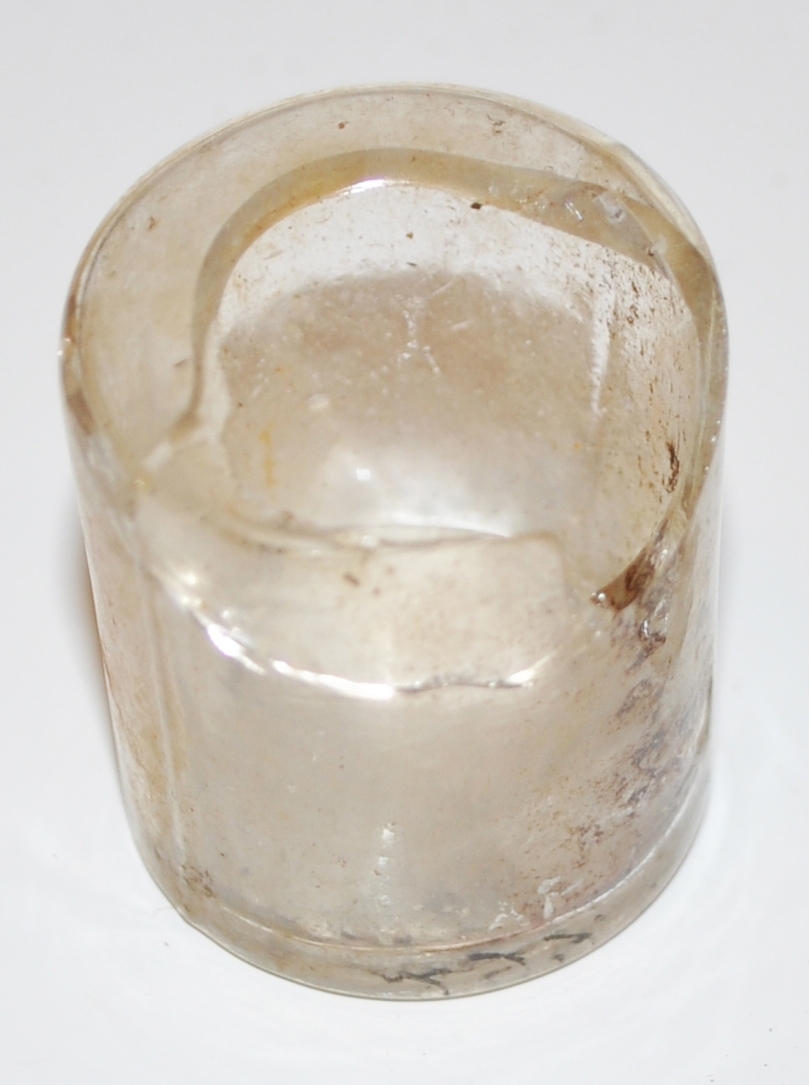 Cylindriskt fragment av glasflaska, tillhör flaskan (APXP.248) och var fastsatt vid denna. Har haft anilinfärgat innehåll.