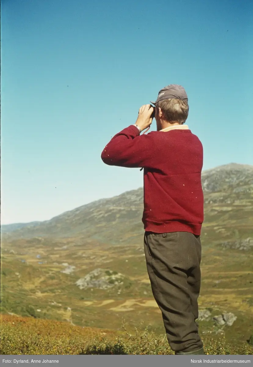 Bjørn Dyrland kikker utover fjellandskap over Åmotdalsfjellene med kikkert