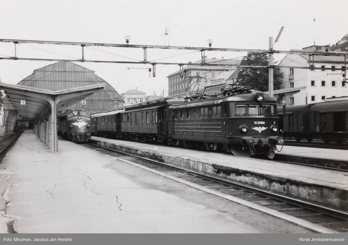 Elektrisk lokomotiv El 11 2080 med persontog på Bergen stasjon. Til venstre diesellokomotiv Di 3 617