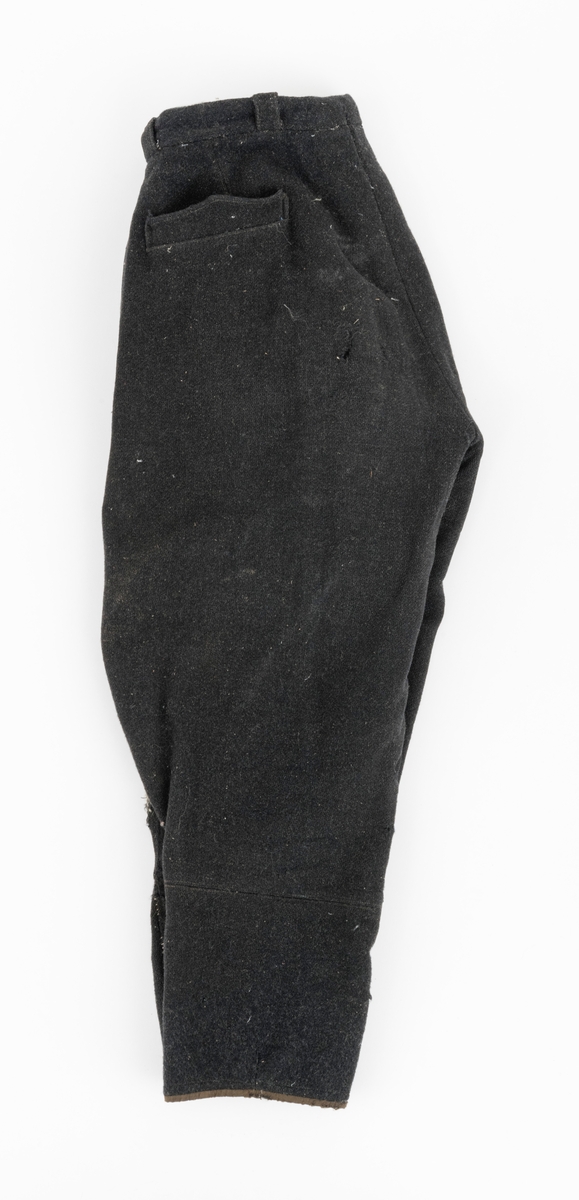 Vadmelsbukser som har vært brukt i 1920-30 åra. Innvendige lommer av bomullsstoff. Buksa er antagelig hjemmesydd. Stoffet på innsiden av linningen er i kunstsilke.