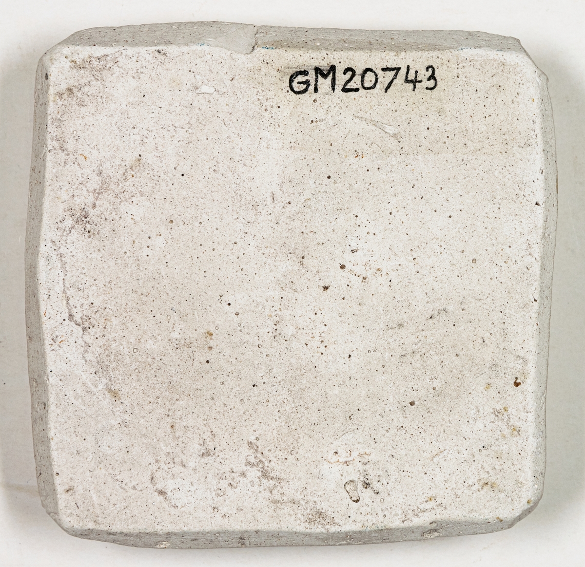 Gjutform av gips. Platt, närmast kvadratisk med fyrsidig bladrosett i omvänd relief på ena sidan. Formytan gråbrun.