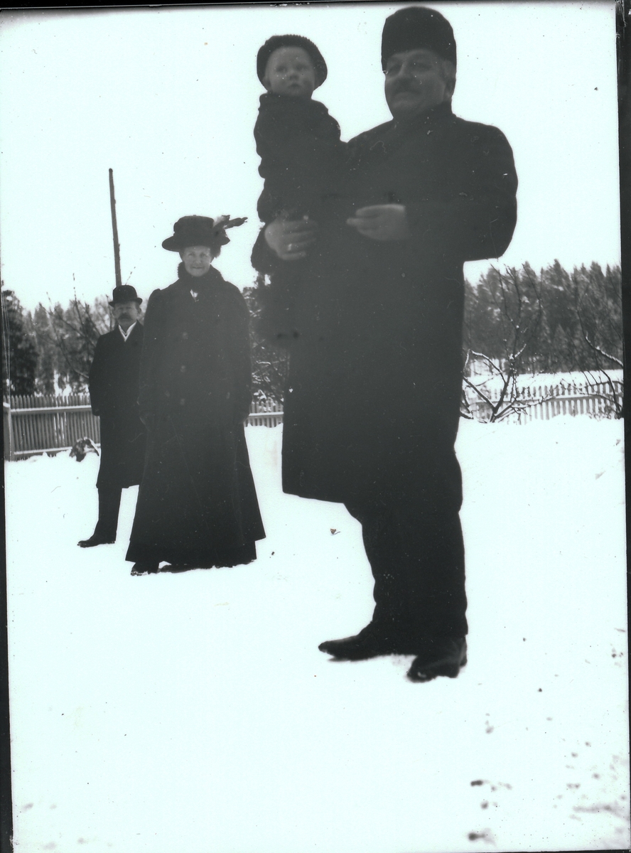 Bestyrer Wilhelm Rydgren med yngste sønnen, Wilhelm Fredrik, på armen. Fru Nicoline Rydgren og gårdseier Ole B.Berger står bak ham. De står i hagen utenfor bestyrervillaen på Kistefoss.