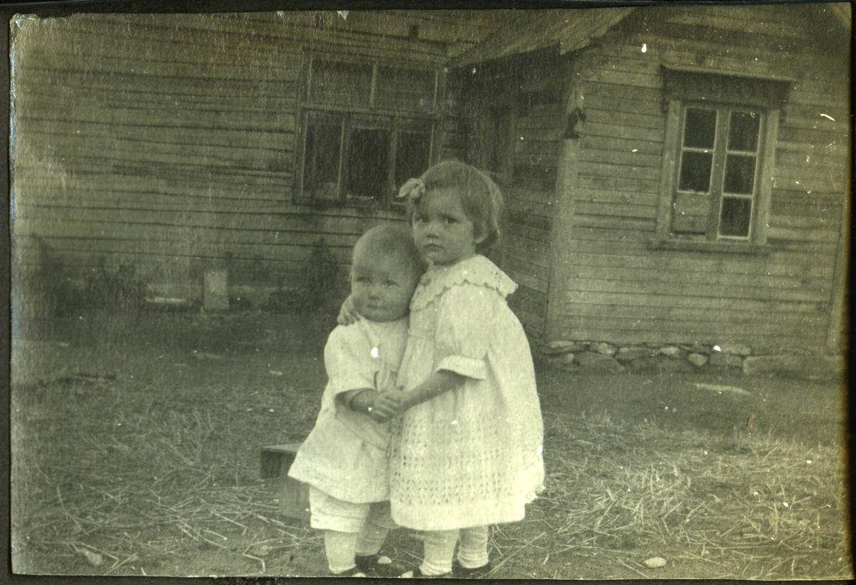 To små barn foran et hus.