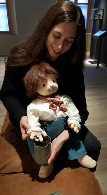 En dame sitter med en dukke på fanget