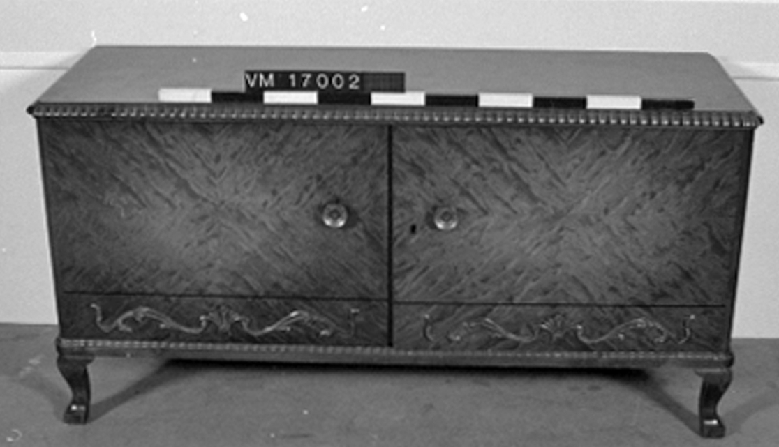 Buffé. Buffén har 2 dörrar, invändigt 2 små backar och 2 hyllor.

Ingår i ett möblemang innehållande bord, buffé och skåp.

Motiv/dekor Reliefdekor, typisk för 1940-talet