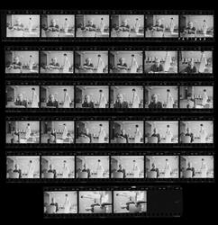 Porträtt av en man i interiör med en stående kvinna i bakgru