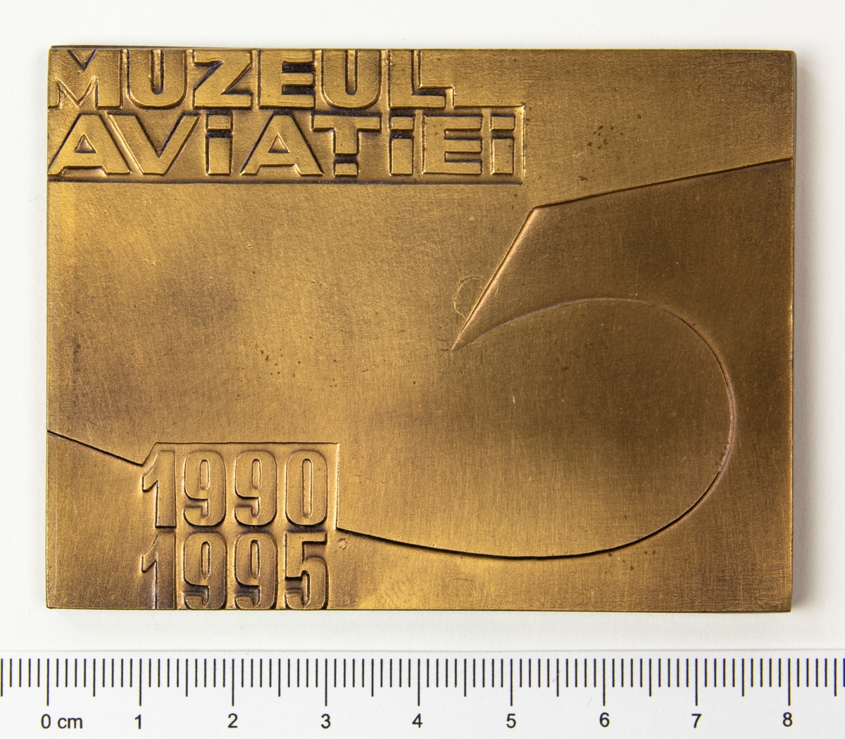 Minnesplakett med motiv av en örn med en sköld på bröstet och texten MAV, årtalen 1990 och 1995 på framsidan. På frånsidan texten Muzeul Aviatiei. Plaketten förvaras i en brun ask.