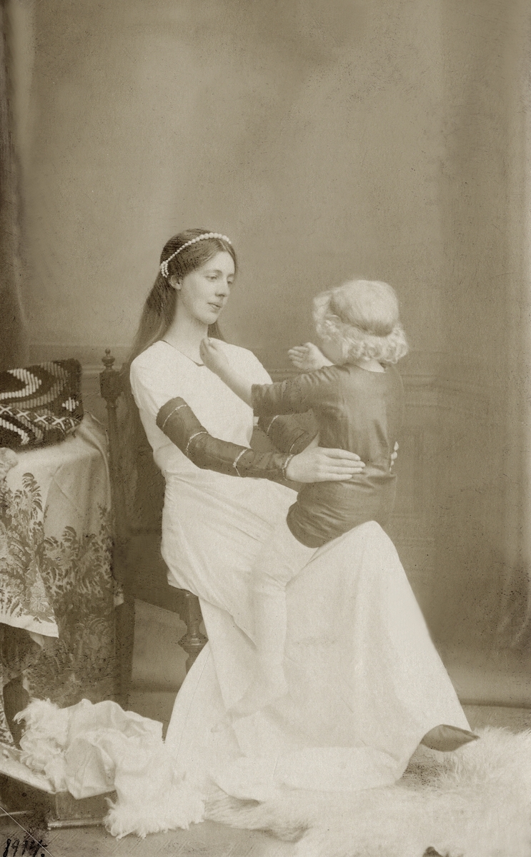 "Rida ranka". Foto, tablå, 1914.
En ung kvinna, Blanka av Namur, leker med sin son på knäet.