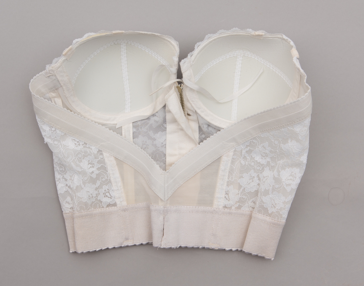 Stroppløs hvit brystholder med spiler. Glidelås og hemper i front. 1950-talls. Blondepynt. Merkelapp: "Loveable"