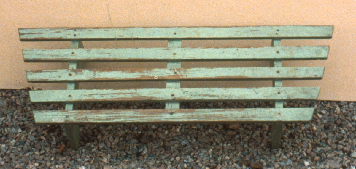 Grönmålad skohylla bestående av fem platta spjälor på profilsågade benstöd.

Neg.nr. 1987-04