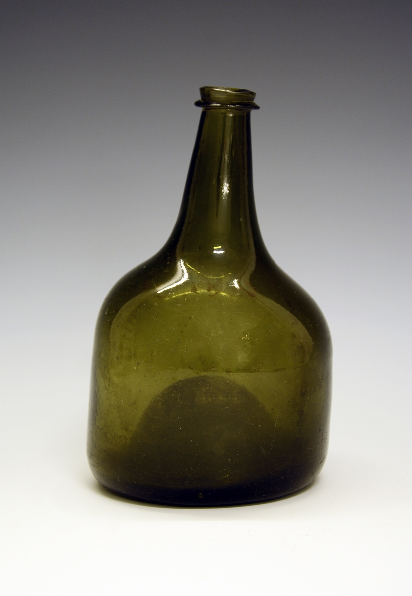 Flaske. Fra protokollen: Flaske av grønt glas, klumpet og skjev, stor hulning i bunden.