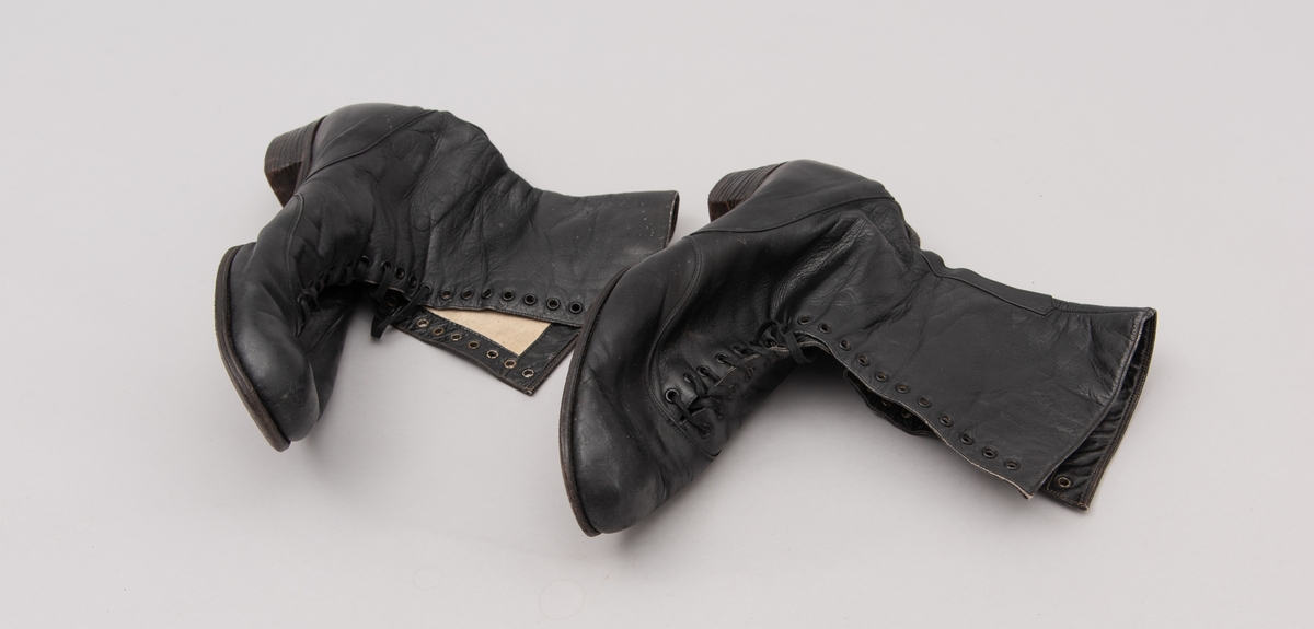 Et par damestøvler i sort lær med snøring. Laget av AS Raade skofabrikk, Moss.