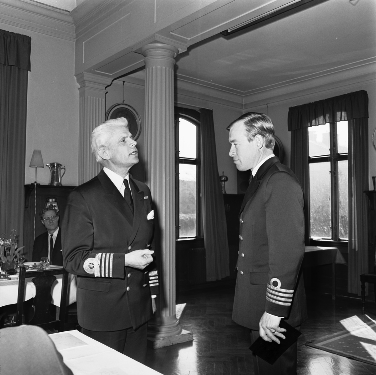 Bilden visar två svenska sjömilitärer i samtal. Stående till vänster är kommendör av 1. graden Harry Engblom, detta året avgående chef för Västkustens örlogsbas.