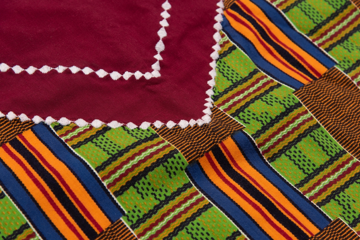 En afrikansk mangemønstret og mangefarget kjole og et rødt sortmønstret skjerf. 
Kjolen ble brukt som UNICEFs regiondirektør for Vest- og Sentral-Afrika i perioden 1994-98. I Kvinnemuseet samling inngår også foto av Torild Skard på jobb med denne kjolen og skjerfet.