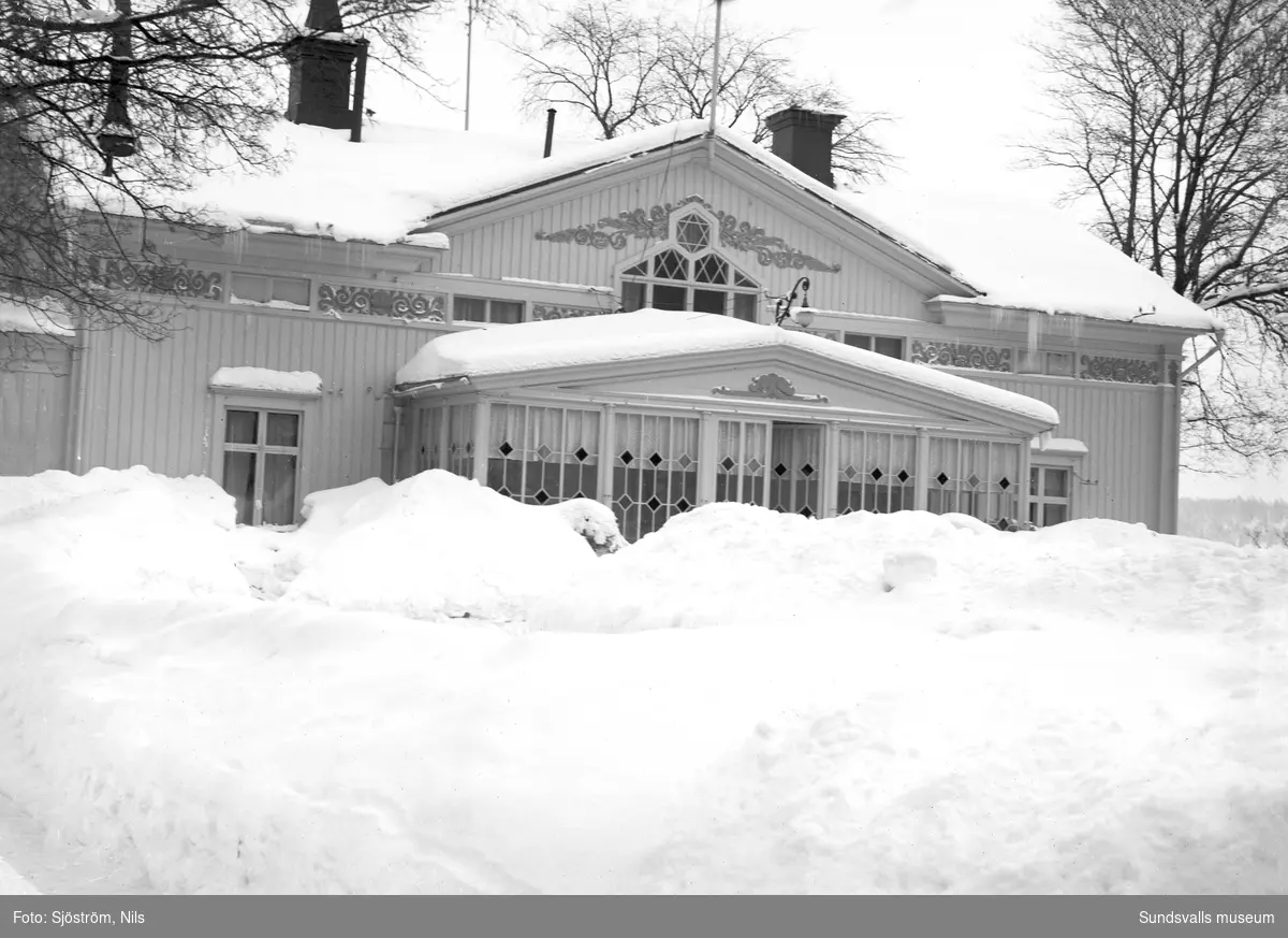 Exteriörbild av Svartviks herrgård där glasverandan skyms av höga snödrivor.