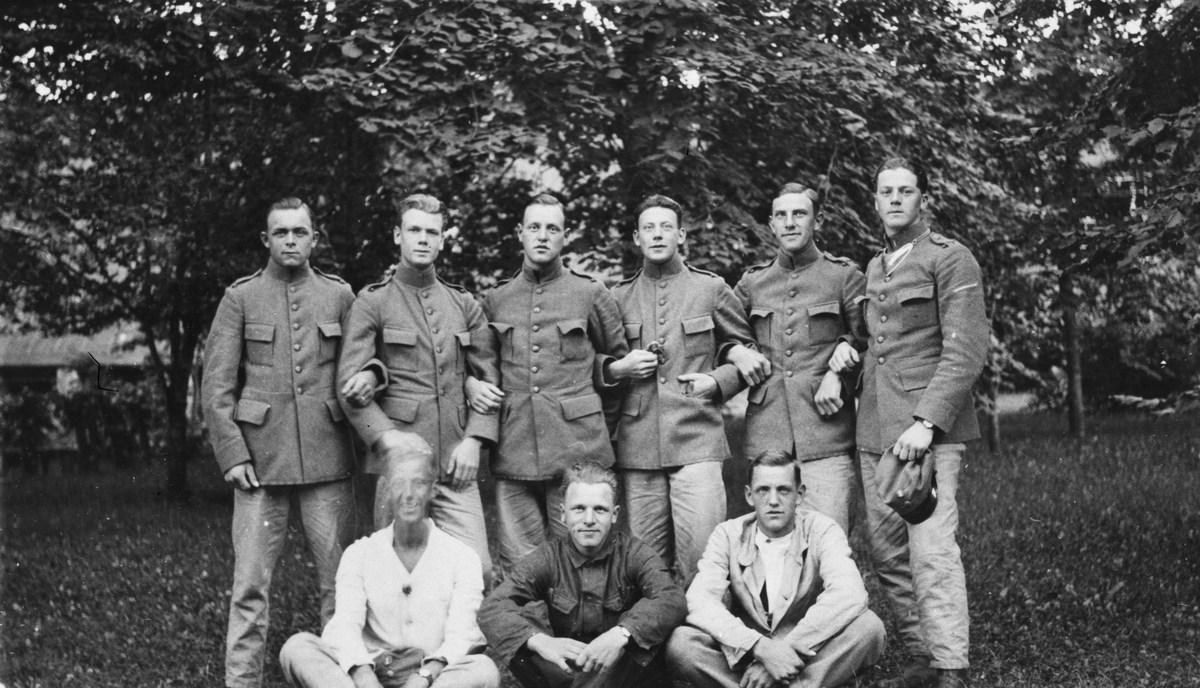 Porträttfoto av nio militärer uppställda utomhus, 1910-1920-tal.