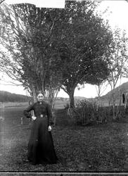 Kvinne fotografert utendørs, foran noen trær.
