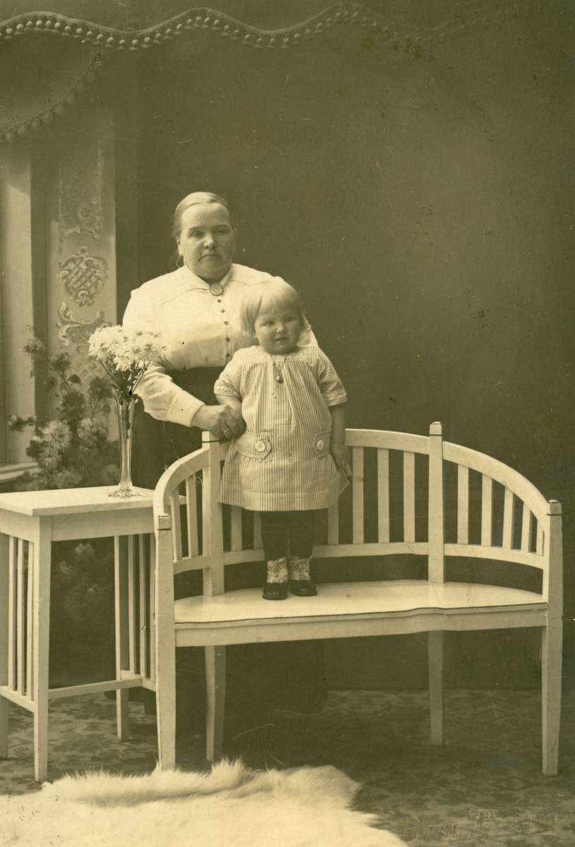 Eldre kvinne og barn i fotoatelier.  Kort sendt til Bergit Johannesdotter Nordbø, frå Gunhild Roe.