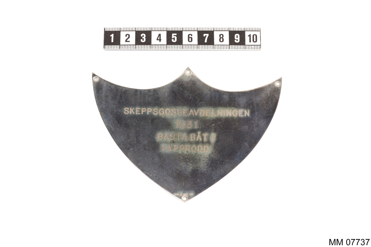 Plakett av silver utan platta.
Inskription: Skeppsgosseavdelningen 1931
Bästa Båt i Kapprodd.