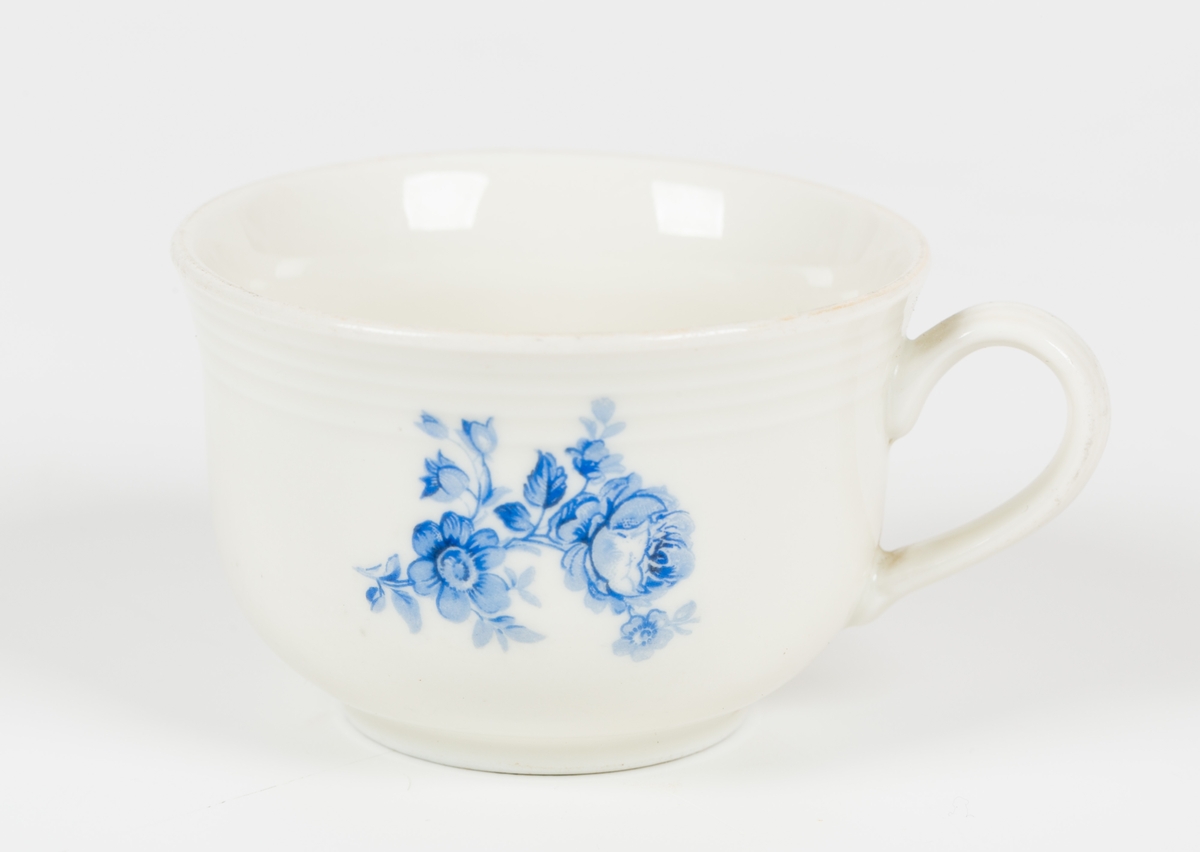 Hvit kopp med blå blomsterdekor.