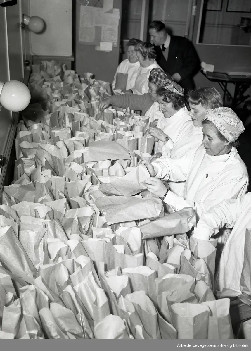 Personalet ved Norsk Folkehjelp pakker gaveposer til juletrefest for barn ved sosiale institusjoner i Oslo. Desember 1951