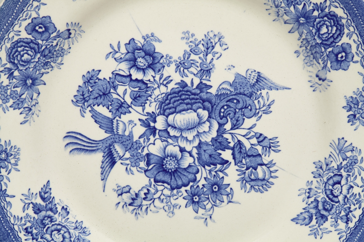 18 hvite tallerkener, dekorert med blått fasanmønster.