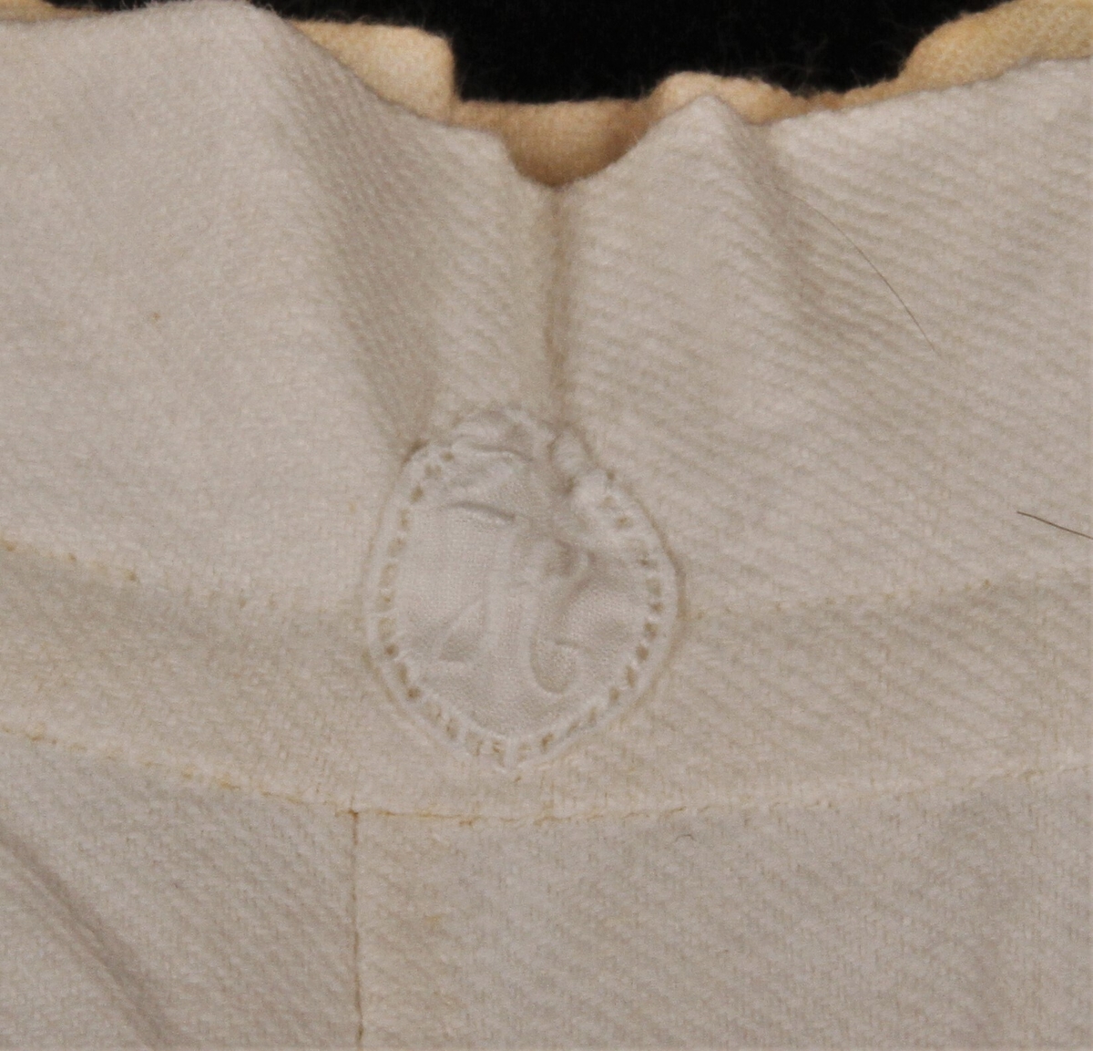 Mamelukk med knytebånd, bakstykket er rynket ved linningen for å gi god plass, innfelt skrittlapp, et utydelig tusjmerke B E (Balke Eldrehjem)